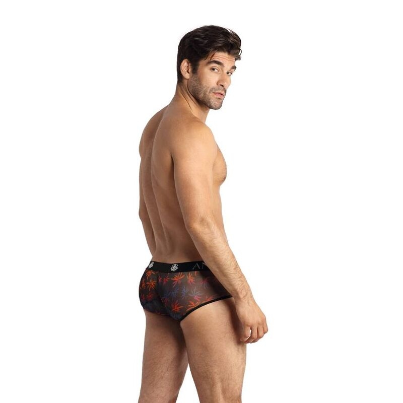 Man standing with his back turned, wearing dark patterned men's underwear against a white background, showing the side profile of his torso and legs.