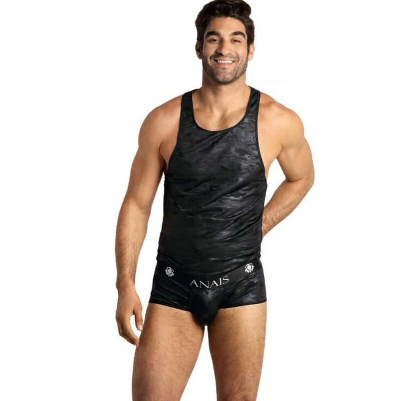 Man modeling a black camo tank top and matching briefs against a white background, smiling at the camera.