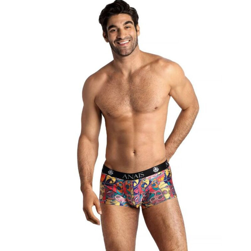 Smiling male model wearing colorful patterned men's boxer briefs with a black waistband that says ANAIS, standing with one hand on his hip.