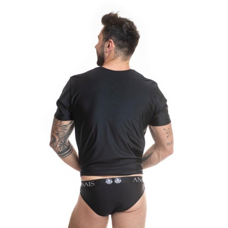 Back view of a man in a black T-shirt and black briefs, showing tattoos on both arms.