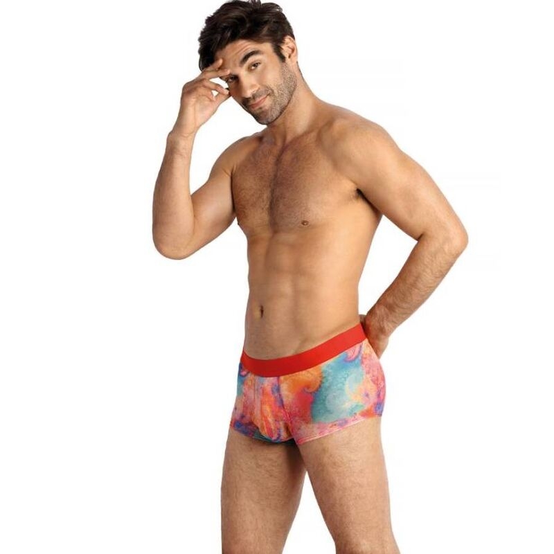 Athletic man wearing colorful patterned boxer briefs with a red waistband, standing with one hand on his temple.