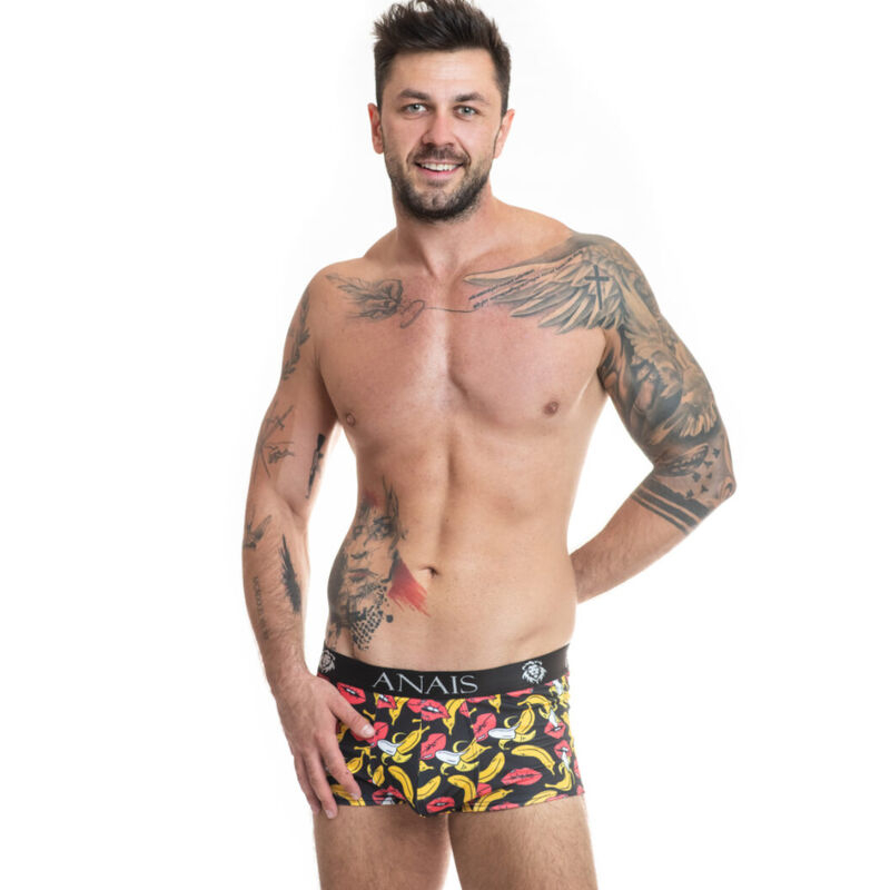 Shirtless man with tattoos wearing black boxer briefs with a bright yellow banana pattern and the Anais waistband against a white studio backdrop.