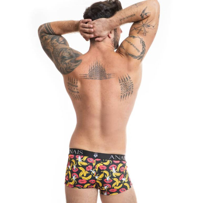 Back view of a tattooed man shirtless, wearing colorful banana-print boxer briefs.