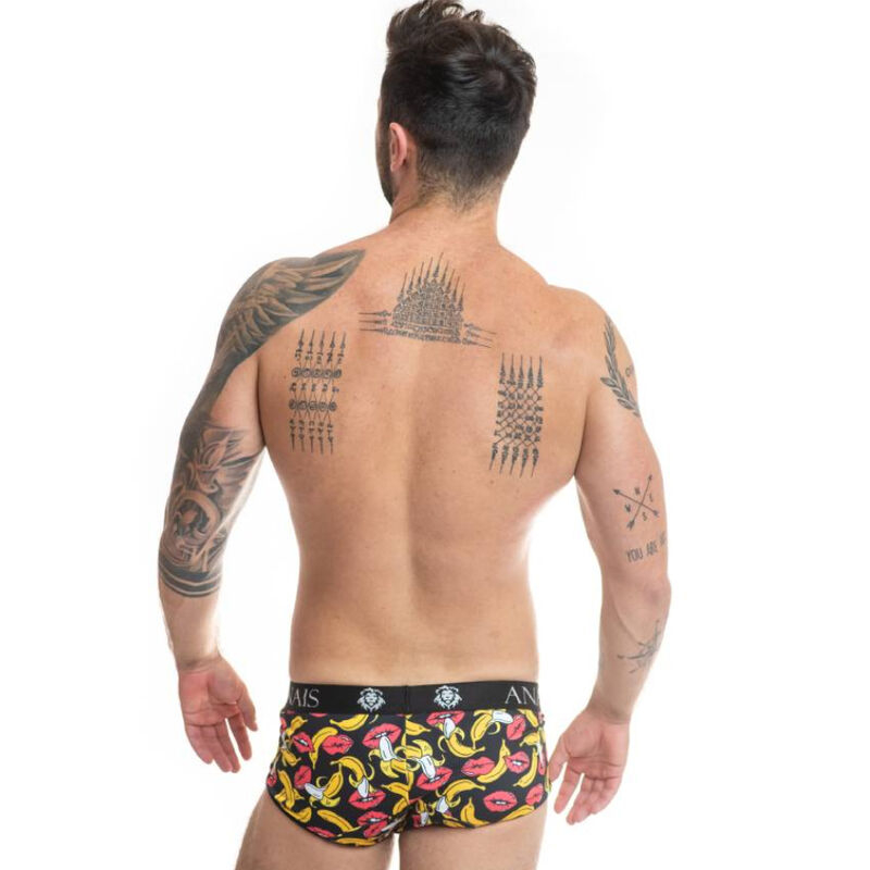Back-view of a tattooed man wearing colorful patterned briefs, standing against a white background.