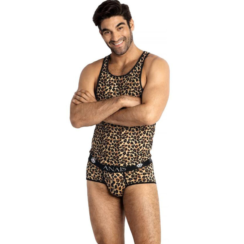 Man posing in a leopard-print sleeveless top and matching briefs, arms crossed, smiling against a white background.