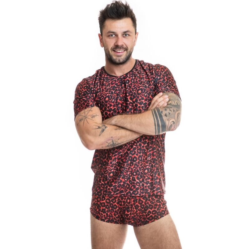 Man with short dark hair and tattoos standing with arms crossed, wearing a red leopard-print T-shirt and matching shorts, smiling against a white background.