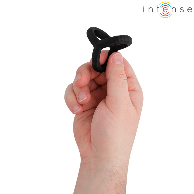 Hand holding a black silicone ring-shaped adult toy between the fingers.