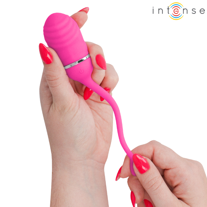 img_223844_73ff660c803dd60d7cab5d87ff66cb52_1png - Sex Shop | Lodia.gr - 100% Διακριτική Και Παράδοση με courier της επιλογή σας Pink silicone vibrator being held between two hands, showing its curved flexible tail and a metallic ring at the base; Intense logo visible in the upper-right corner.