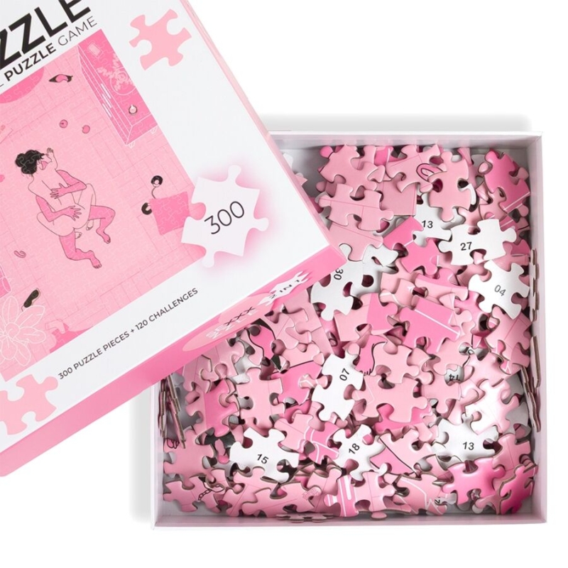 Open pink puzzle box spilling numerous pink puzzle pieces into a white tray inside. The top lid shows a white puzzle-piece icon and pink artwork, suggesting a pink-themed puzzle game.