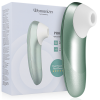 Green ergonomic clitoral stimulation device with white silicone tip beside its light blue packaging labeled 'Womanizer' and 'Pro'.