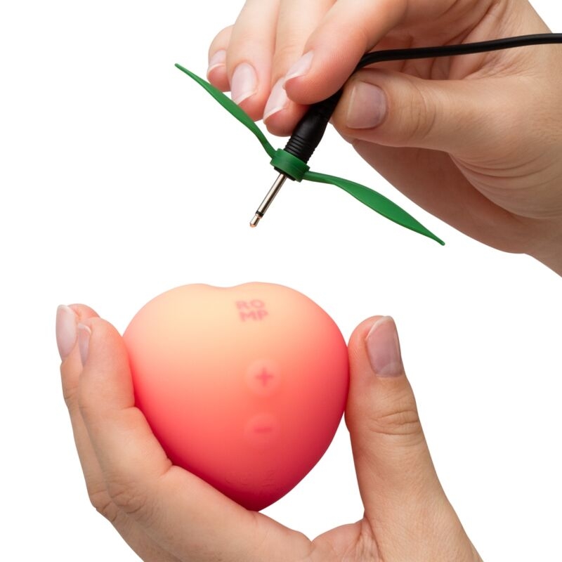 Hands connect a green propeller attachment to a pink silicone vibrating egg with plus and minus buttons on its surface.