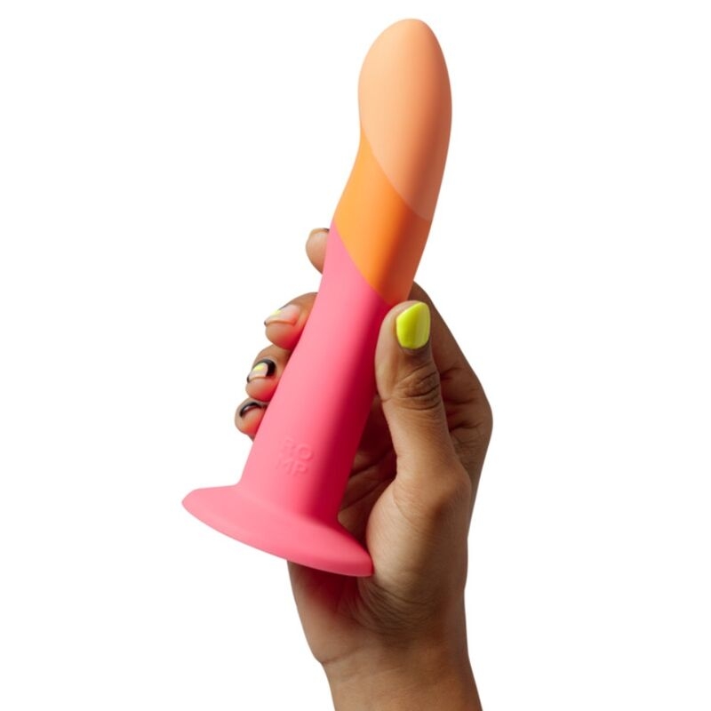 Hand gripping a pink silicone butt plug with an orange-tipped end photographed against a white background.