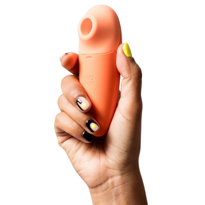 Hand gripping a peach-colored silicone vibrator with a rounded tip at the top.