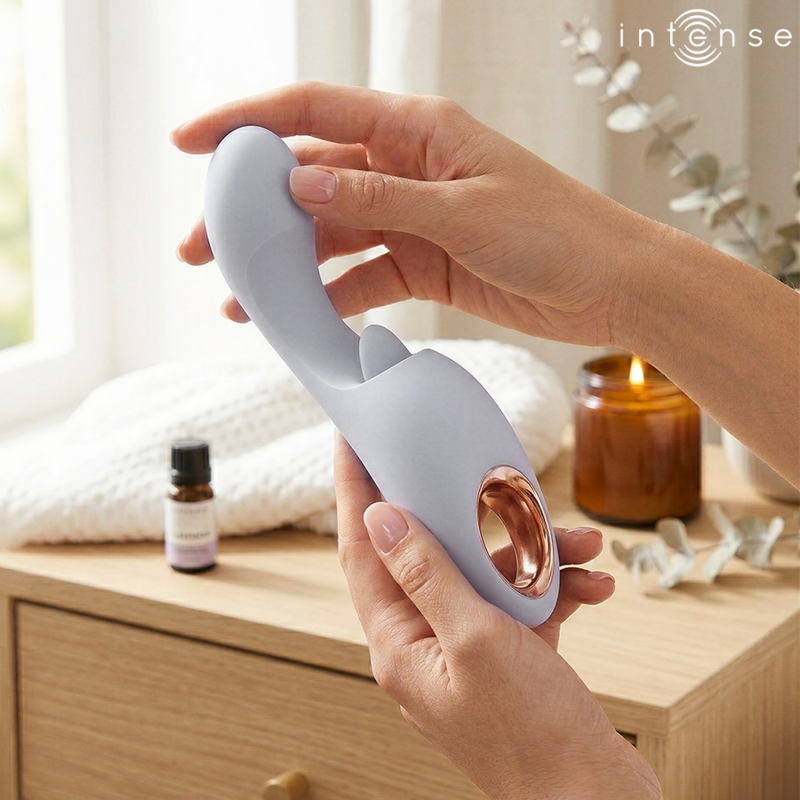 img_227528_bcb12500ec0b606868426576a359d615_1png - Sex Shop | Lodia.gr - 100% Διακριτική Και Παράδοση με courier της επιλογή σας Hands hold a curved lavender silicone sex toy with a bulb end and a metal ring, shown on a bedroom dresser.