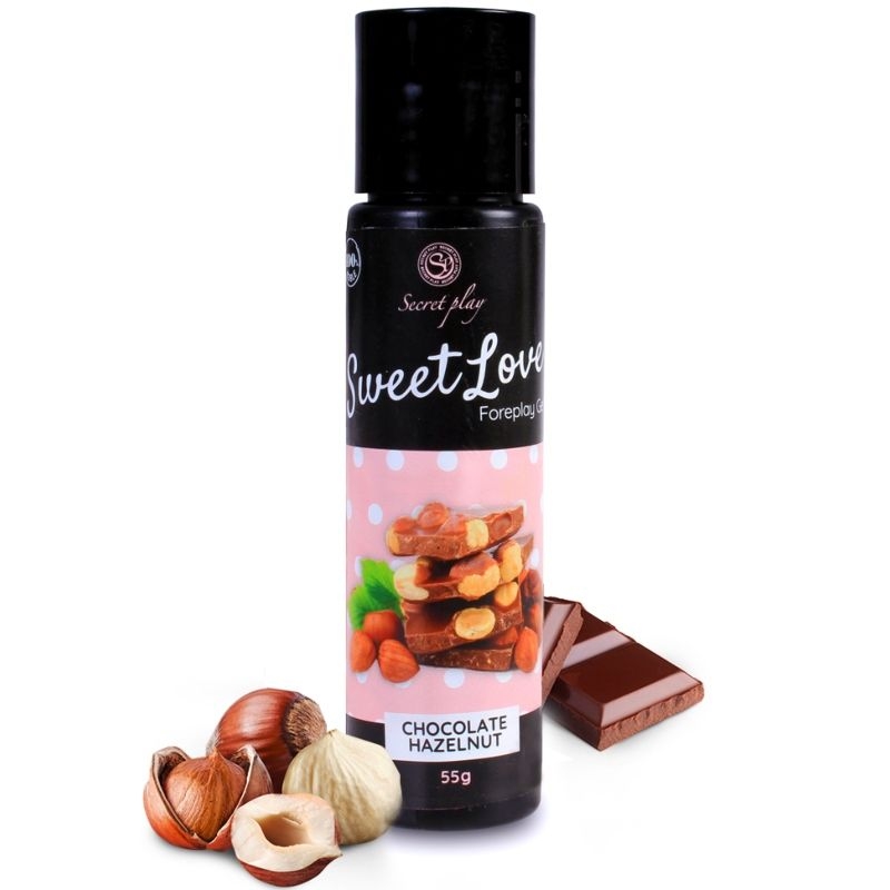 Black-labeled bottle of chocolate hazelnut flavor with chocolate pieces and hazelnuts beside it on a white background